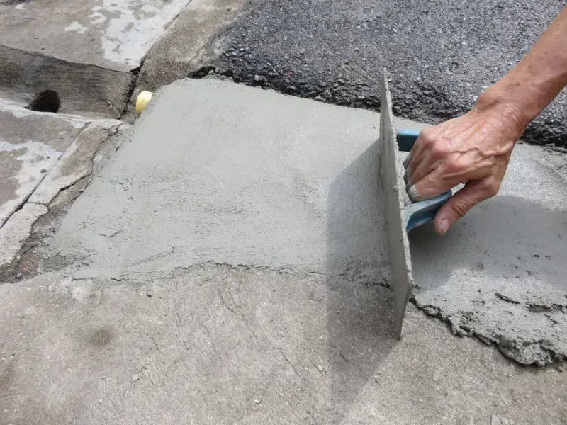 Hand smoothing wet concrete on a sidewalk with a trowel