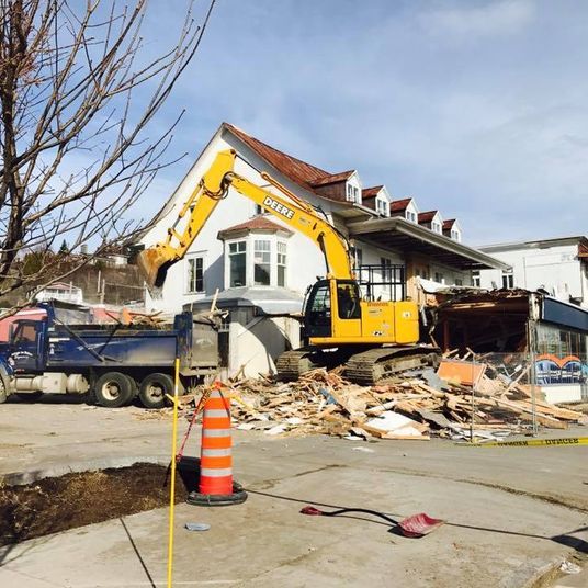 Une grande excavatrice jaune démolit une maison