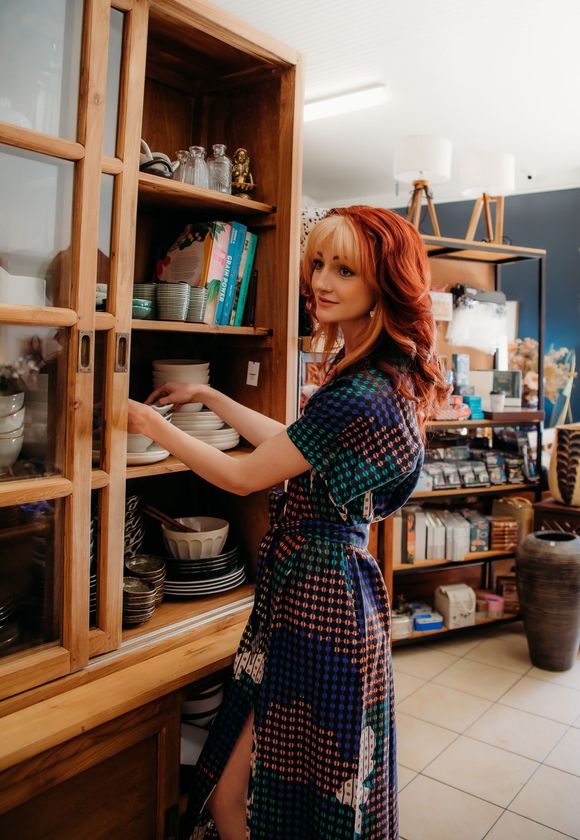 A woman in a dress is standing in front of a cabinet — Lavie Hair & Beauty in Ciccone, NT