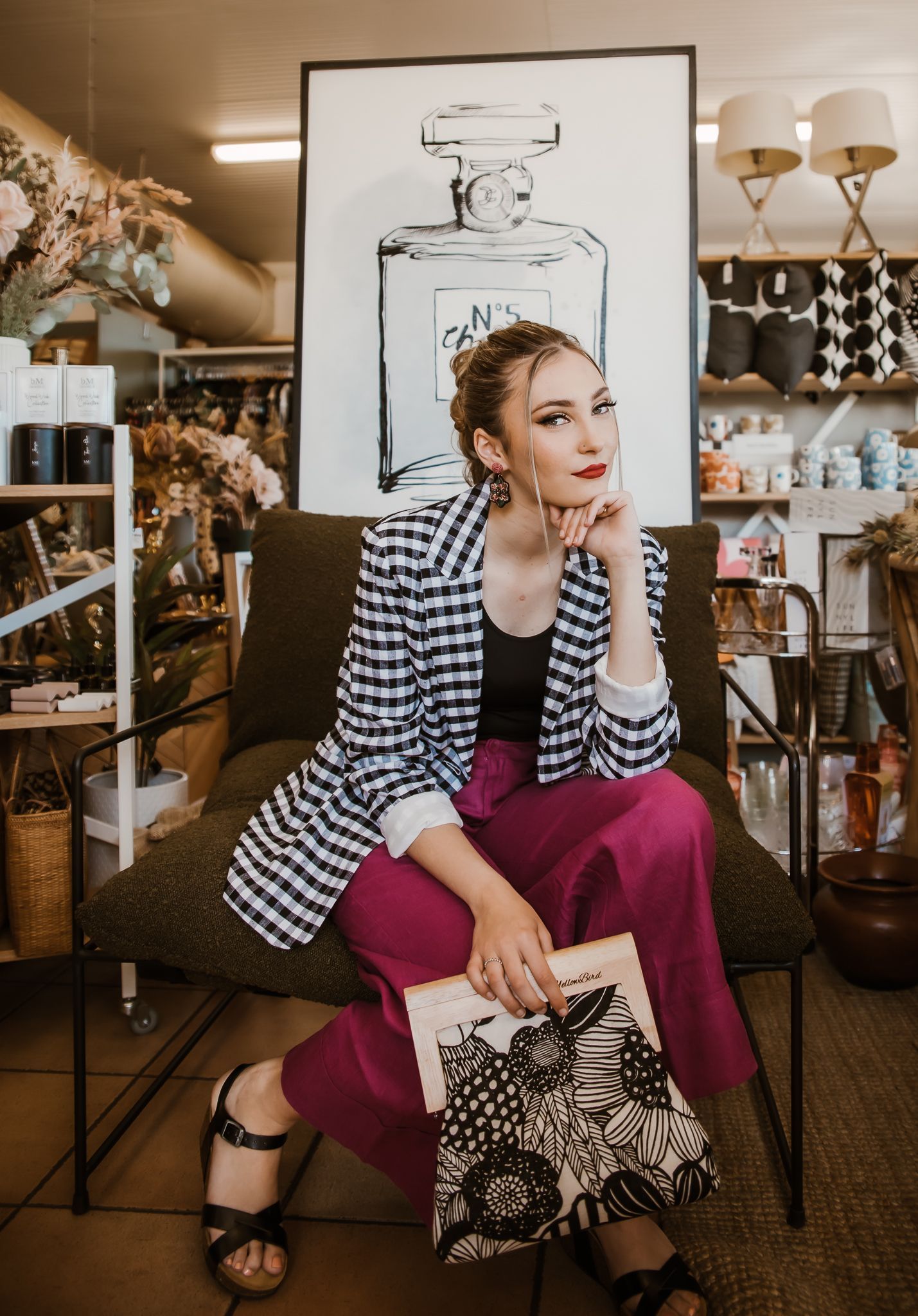 A woman is sitting in a chair in front of a painting of a bottle of perfume — Lavie Hair & Beauty in Ciccone, NT