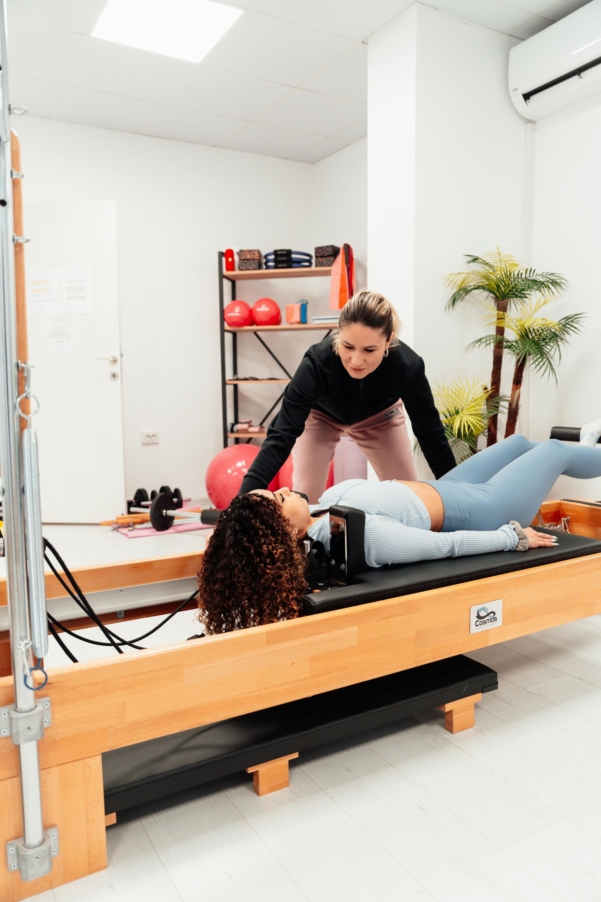 instructor helping guide a woman laying down on a reformer
