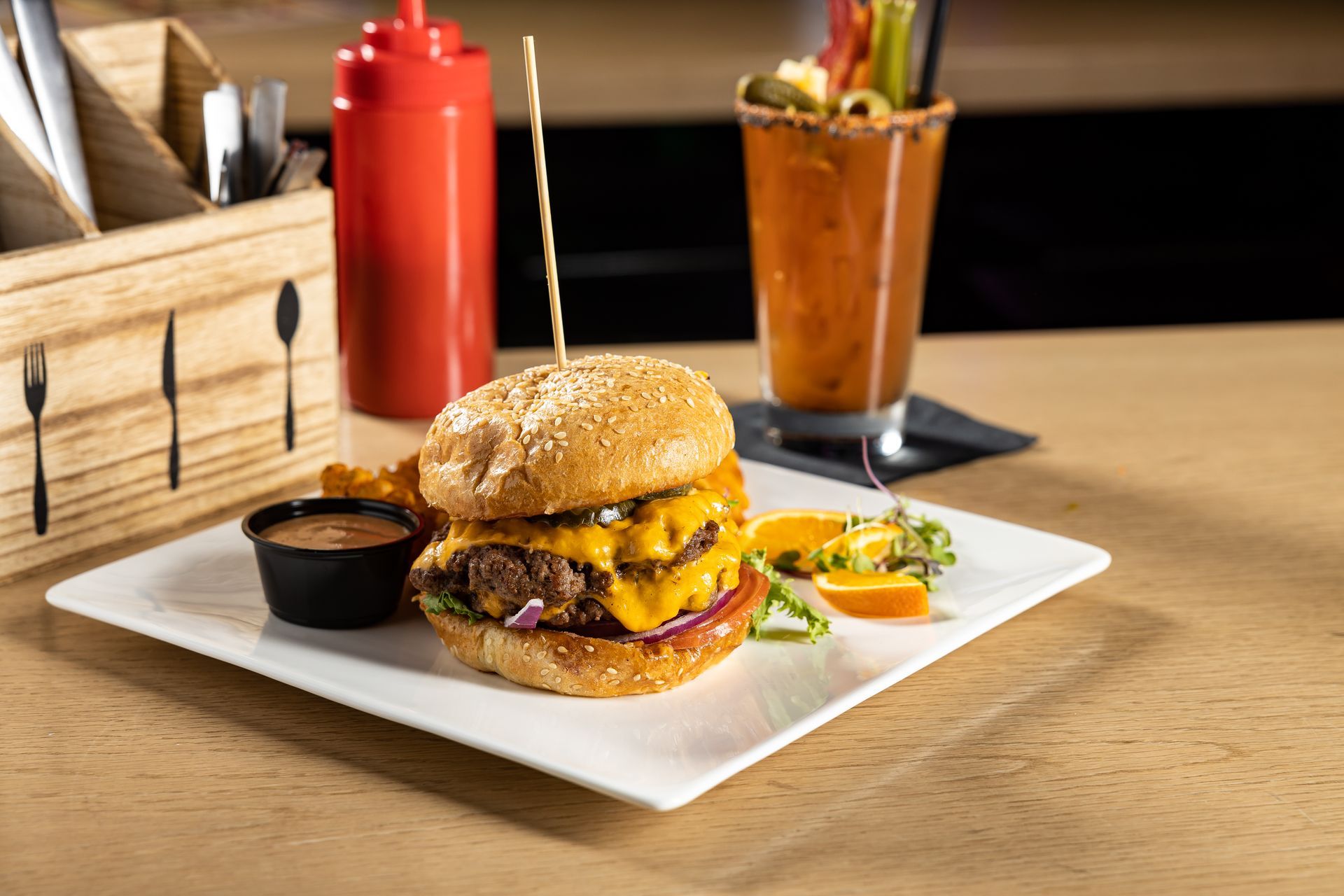 Large burger on a white plate with a margarita at tony tenderonis in denver colorado