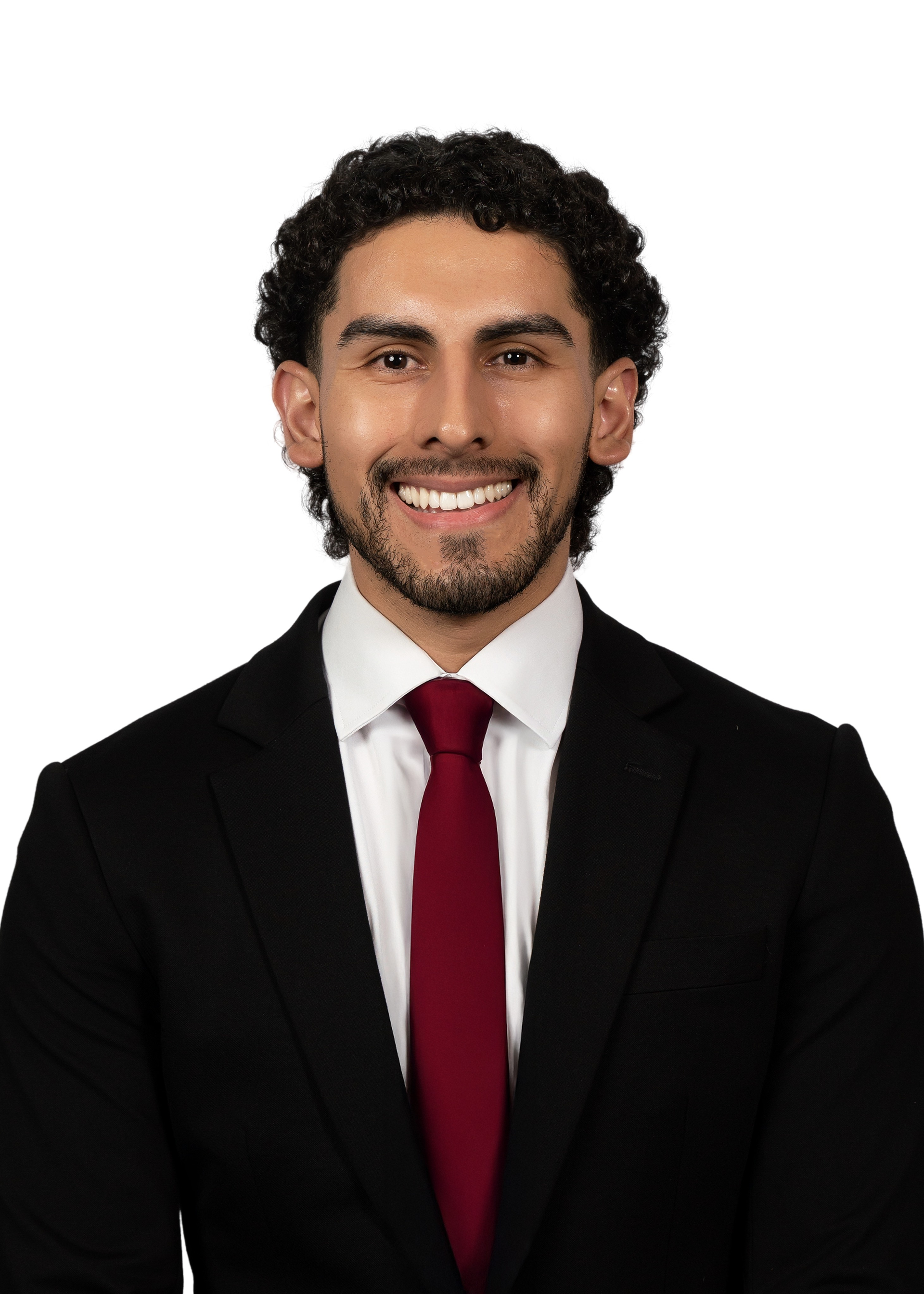 Smiling person in a black suit, white shirt, and red tie against a plain white background