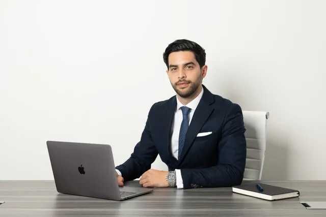 Businessperson seated at a desk with a laptop in a minimalist office