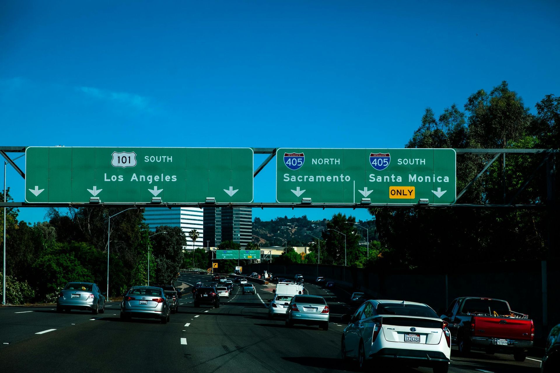 Highway traffic under green overhead signs for Los Angeles, Sacramento, and Santa Monica