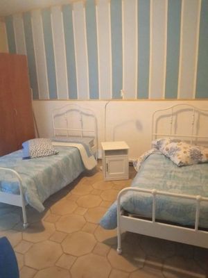 Due letti singoli con struttura in metallo bianco si trovano in una stanza con pareti a strisce blu e bianche.