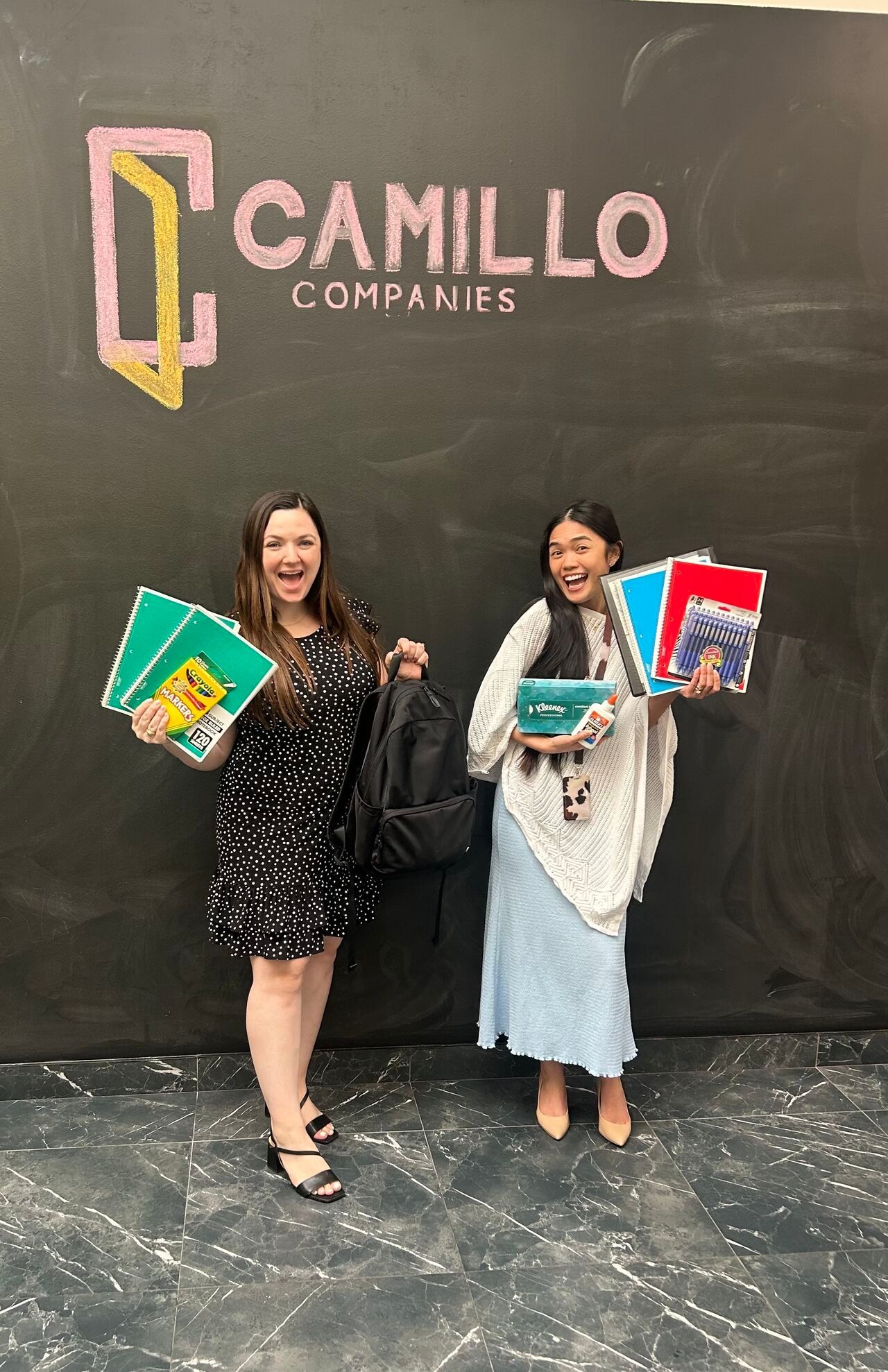 Camillo Companies employees showing sample of donated school supplies
