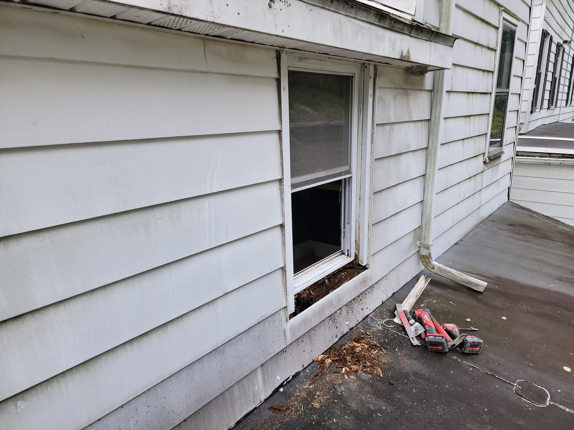 A broken window on the side of a white house