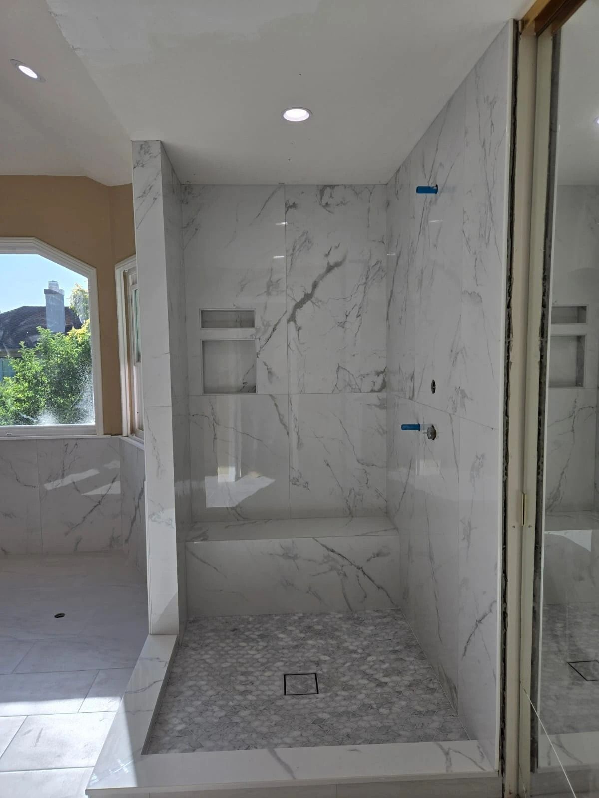 Partially tiled bathroom with walk-in shower, marble-look walls, and recessed ceiling light