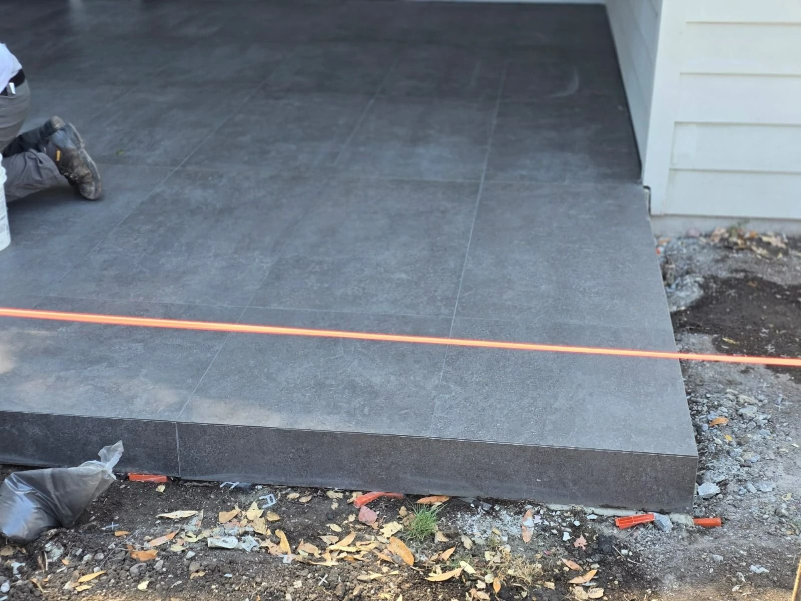 Concrete porch slab with a fresh dark finish and an orange guide line at the edge