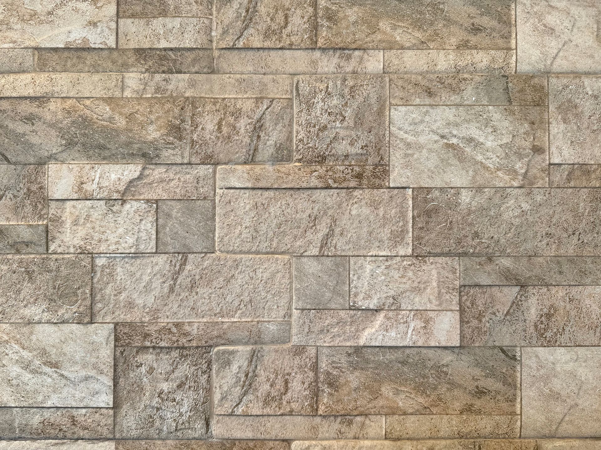 Beige and tan stacked stone wall with a textured brick pattern