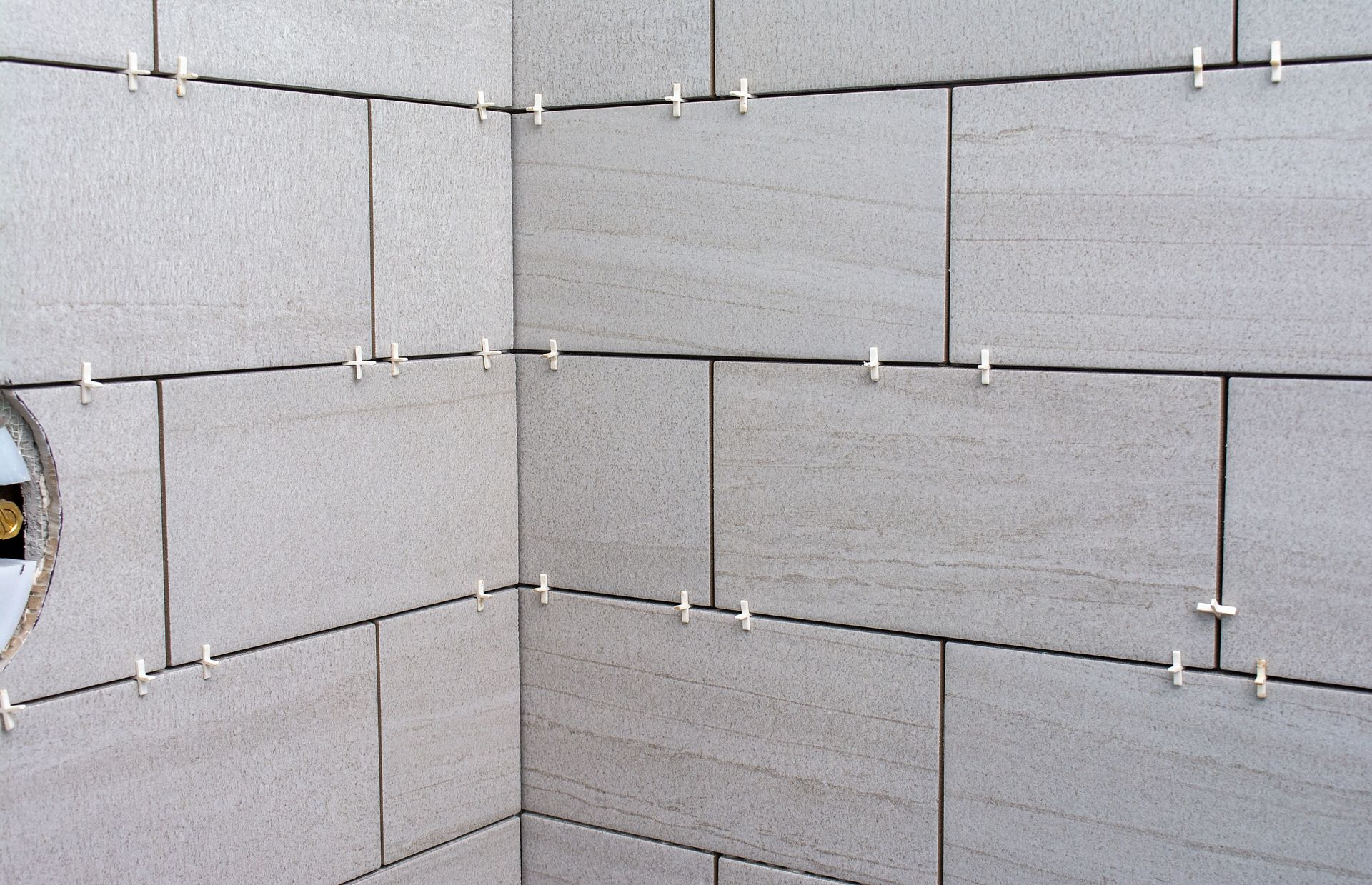 Gray cinder block wall corner with visible mortar joints and a small circular opening on the left