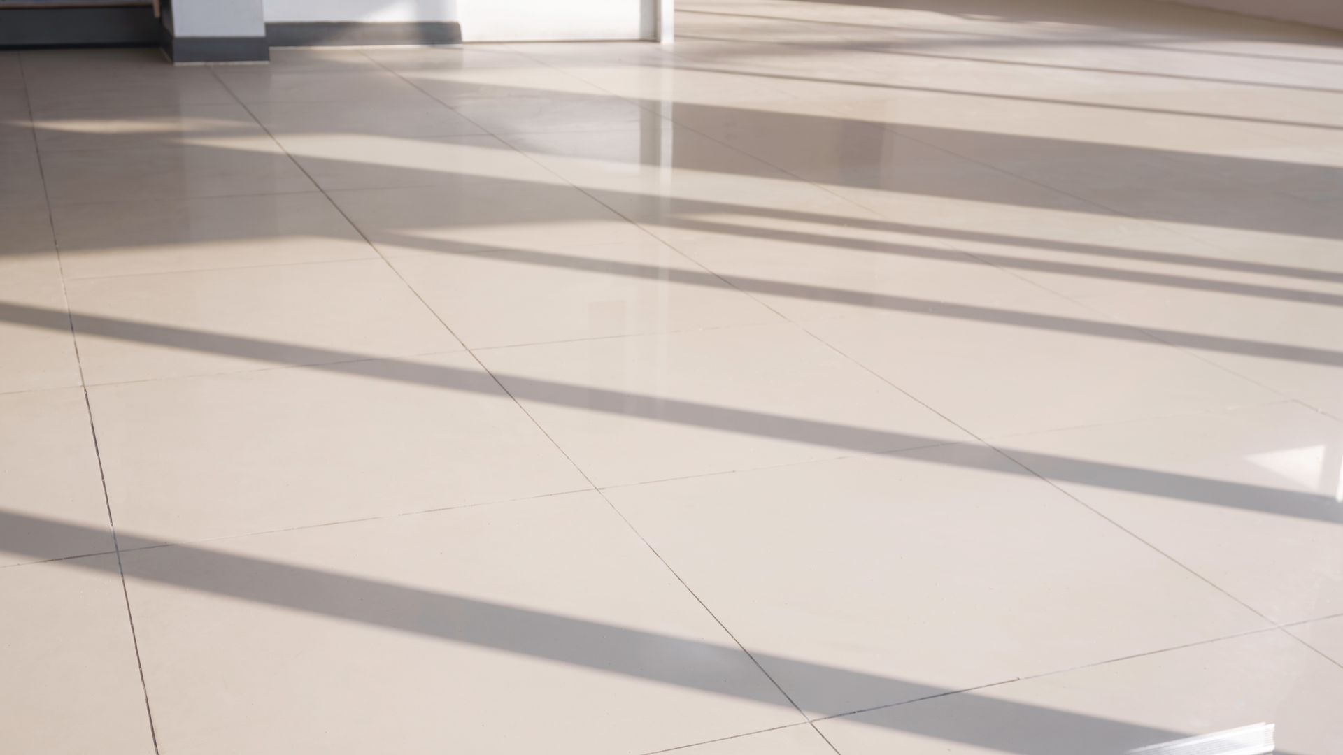 Sunlit tiled floor with long shadows in an empty indoor space