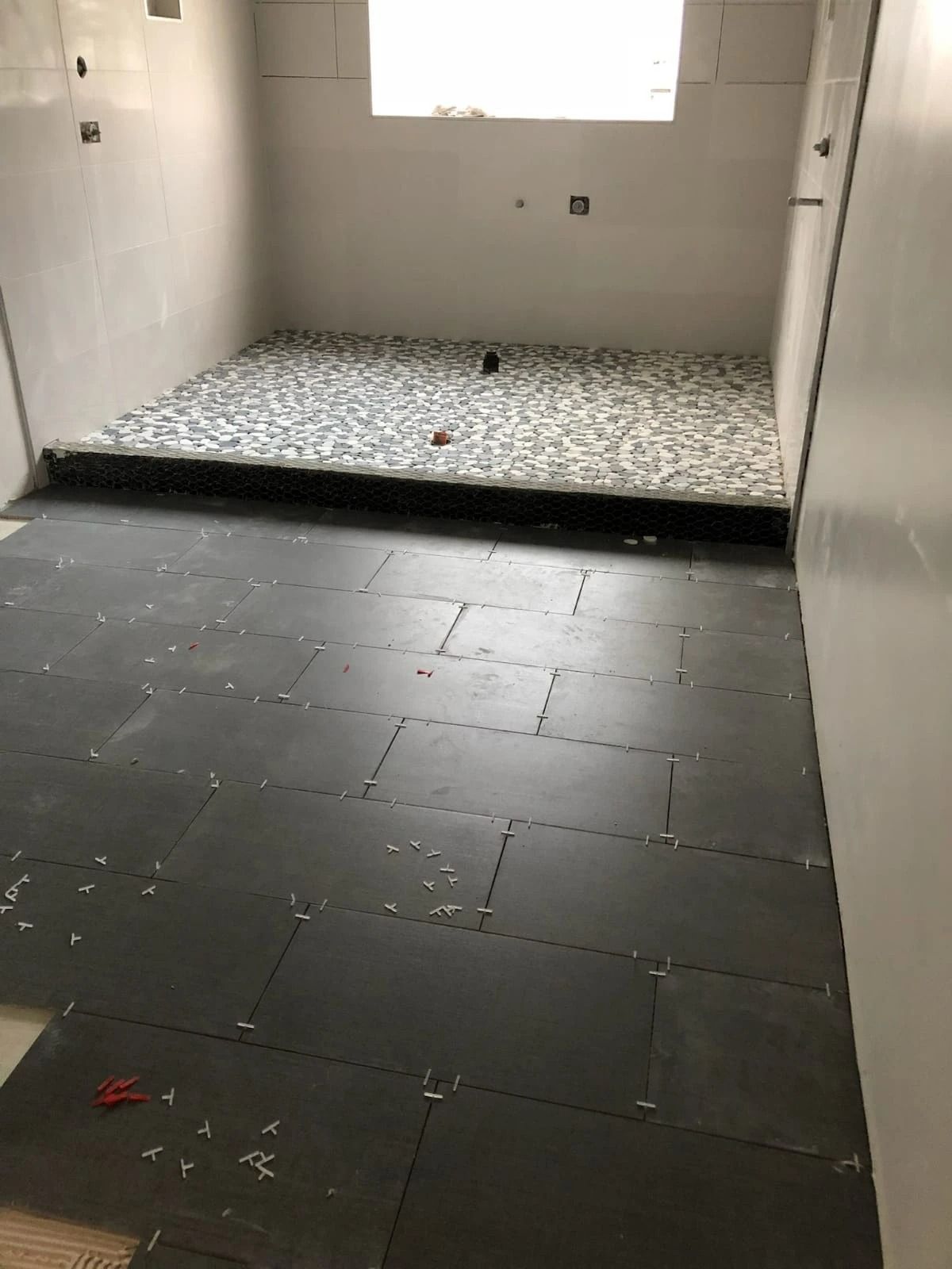 Empty tiled room with a raised patterned platform beneath a bright window