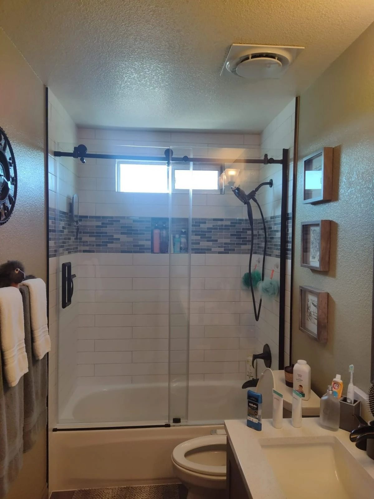 Bathroom with a glass shower enclosure, toilet, vanity sink, and wall decor.