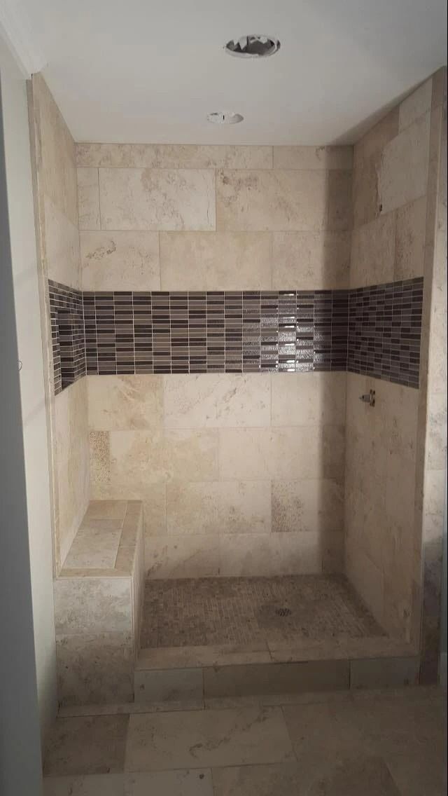 Empty tiled walk-in shower with beige walls and a dark mosaic accent band.