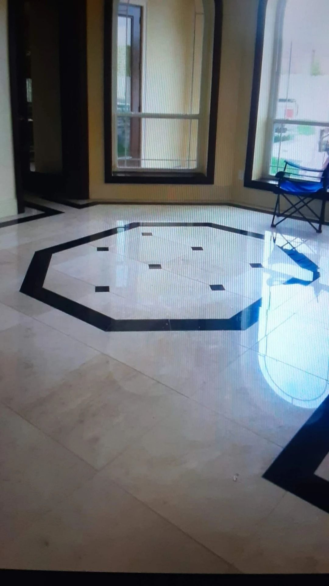 Empty tiled room with a black octagonal floor border and a window at the back.
