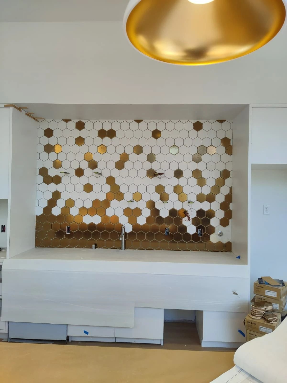 Modern room with gold hexagonal wall art, built-in bench, and a gold ceiling light fixture