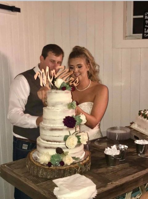 Couple cutting a four-tier wedding cake decorated with flowers.