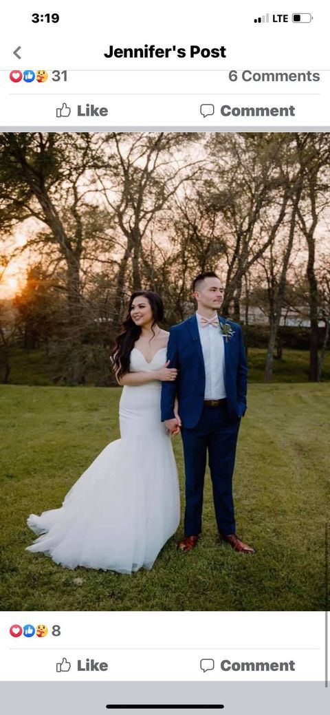 Bride and groom holding hands in a grassy field. The bride wears a white dress, the groom a blue suit.