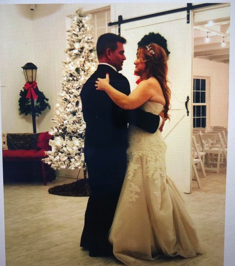 Couple dancing at a wedding reception; decorated Christmas tree in the background.