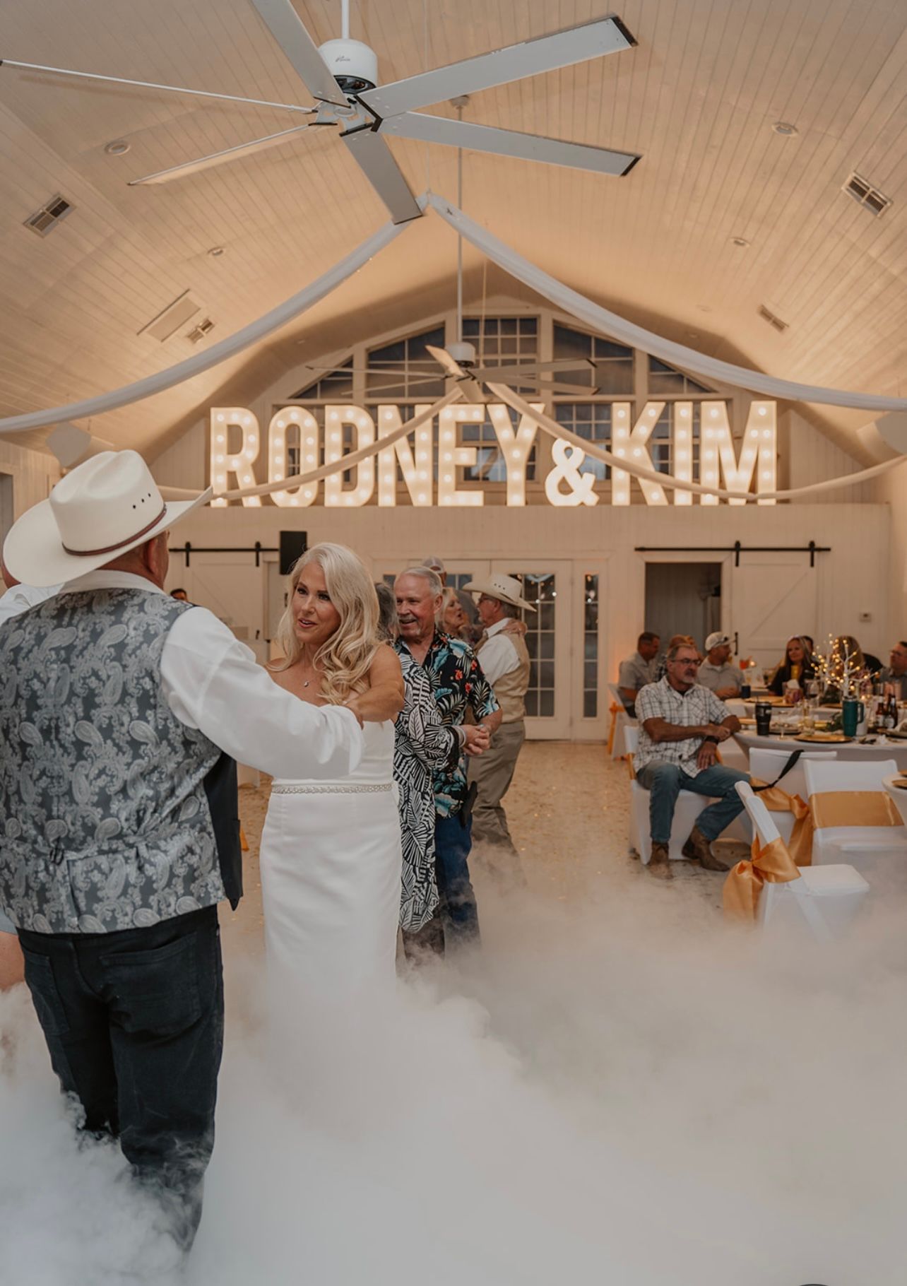 Bride and groom dance on a cloud of fog under a sign that reads