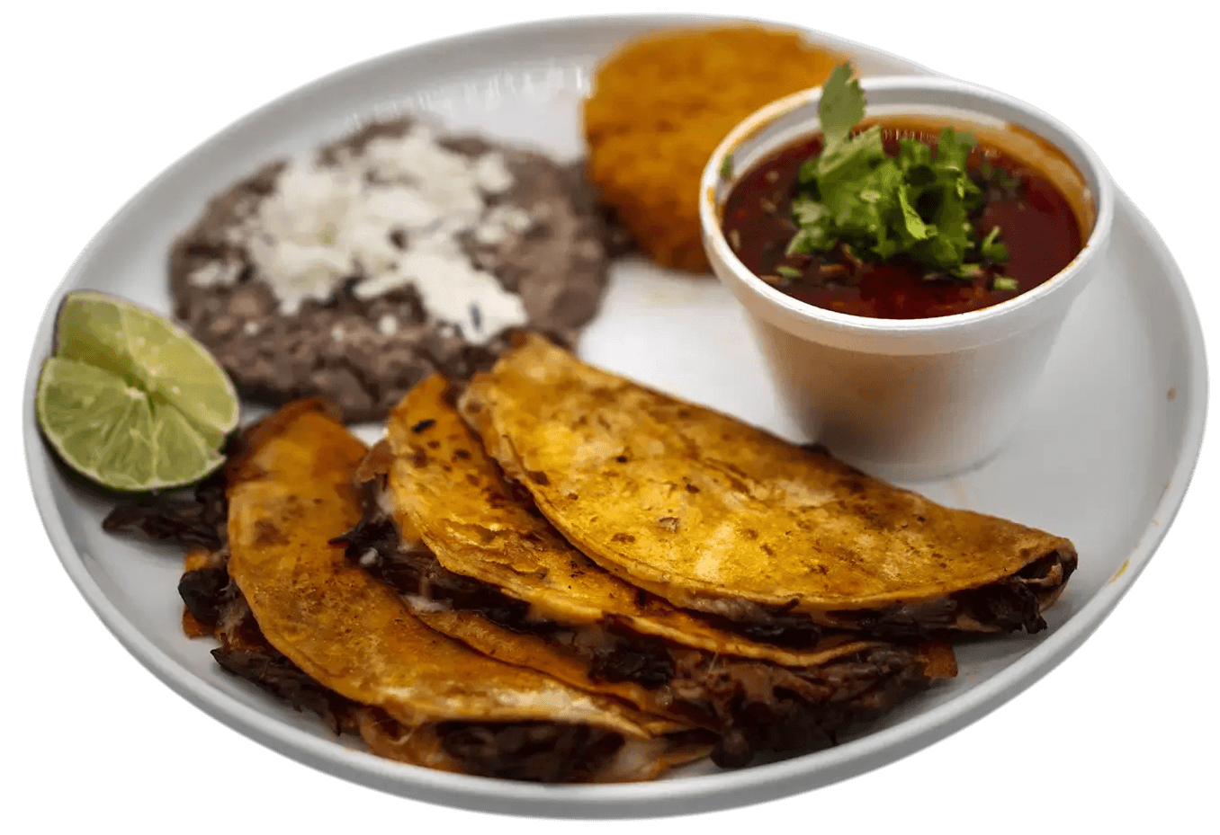 Plate of tacos, beans, and consommé with lime wedge.