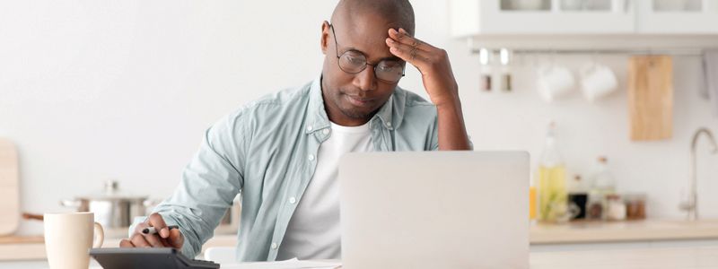 A man is sitting at a table with a laptop and a calculator.