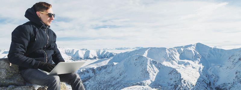 man-with-laptop-on-top-of-snow-covered-mountains
