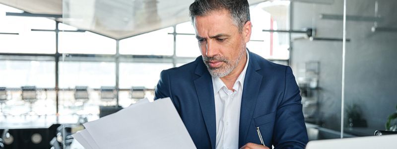 Person beside giant tax form and red pencil with question mark, implying tax confusion