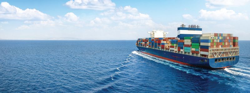 Container ship sailing on a blue ocean under a bright sky