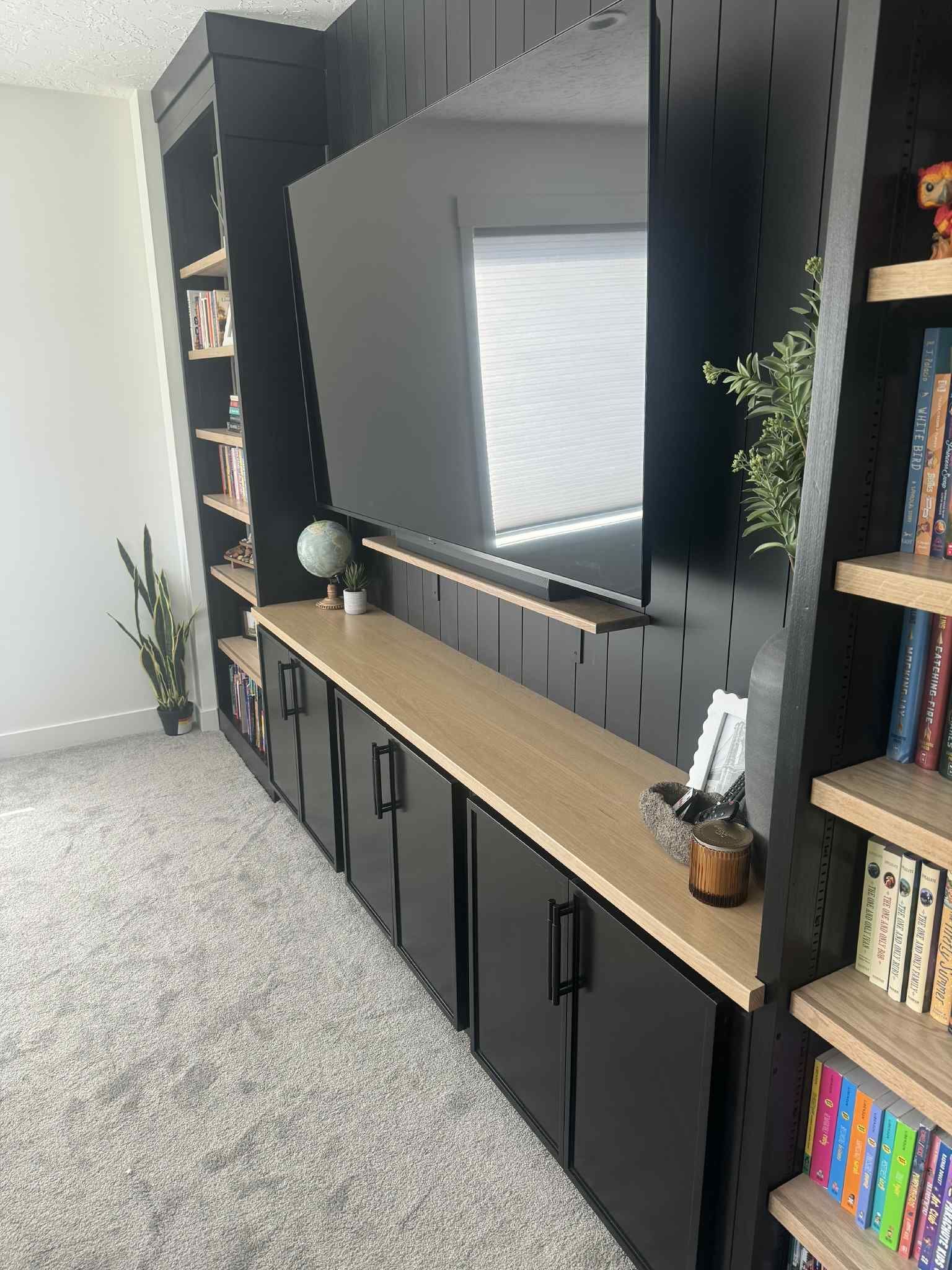 Black entertainment center with TV, cabinetry, shelving, and tan countertop.