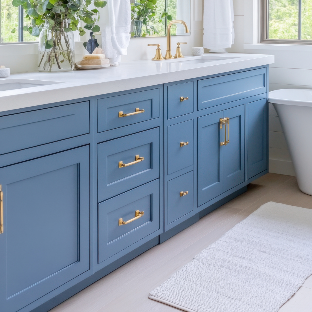 Blue bathroom vanity with gold hardware, white countertop, and rug.