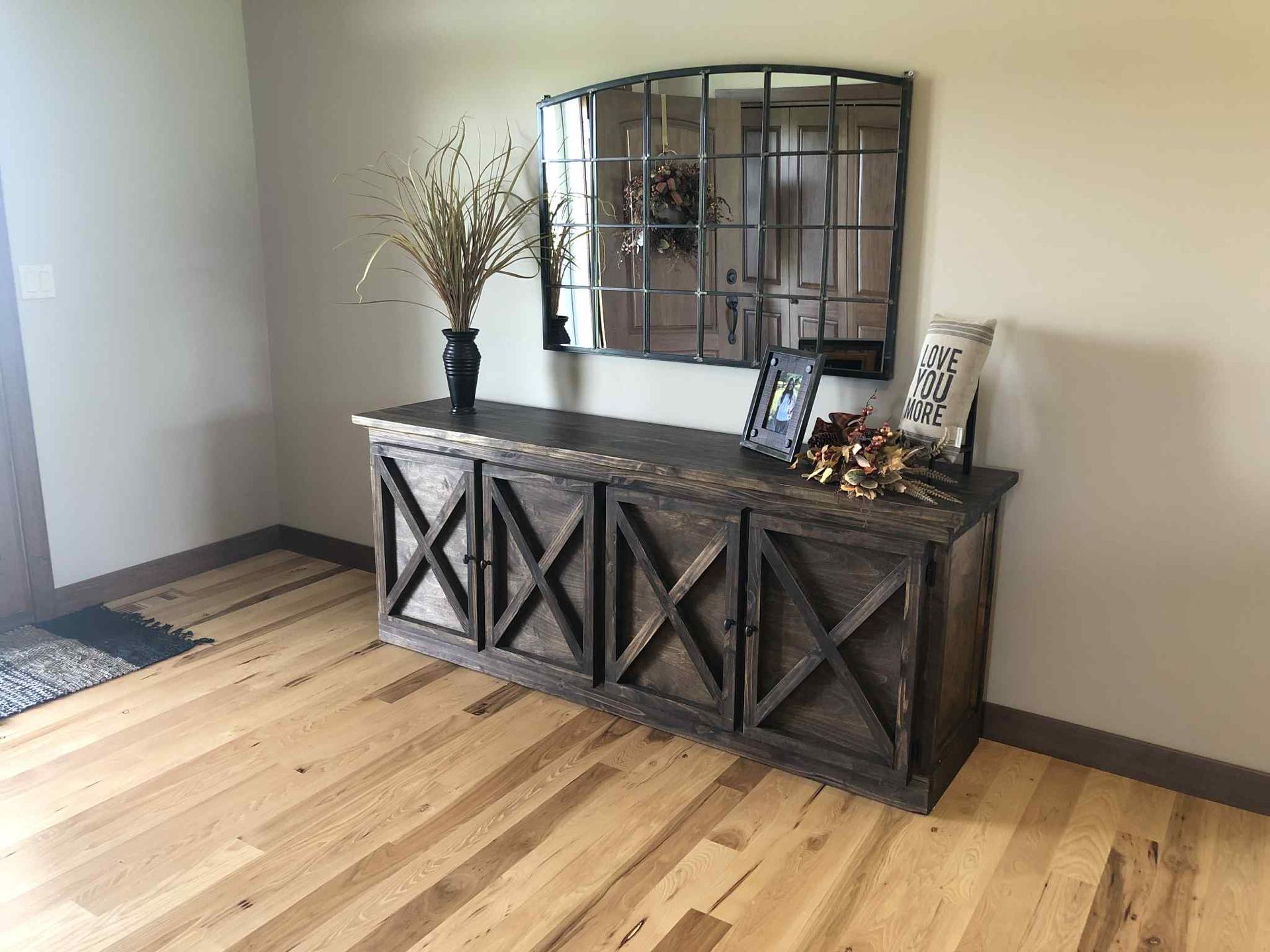 Wooden console table with mirror, decor on wood floor.