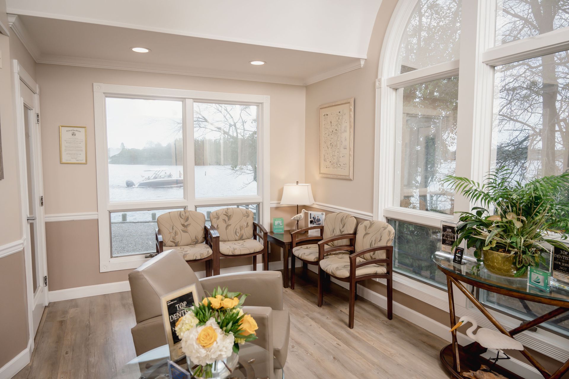 Waiting room with lake view, neutral colors, armchairs, and plants.