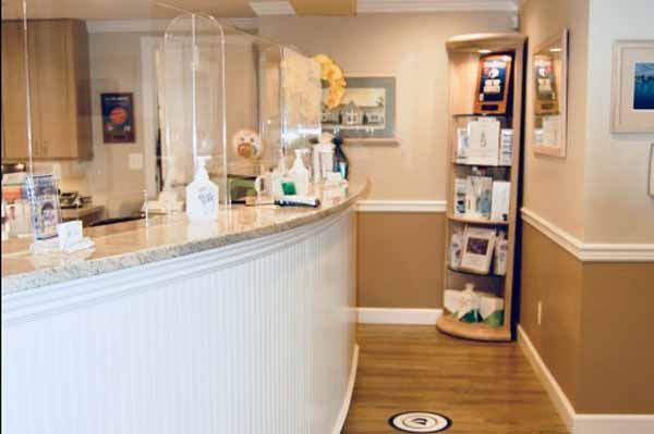 Reception area with a curved white counter, protective shields, and product display.