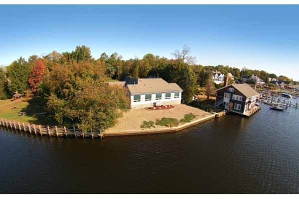 Waterside house with dock and boathouse; surrounded by water and trees.