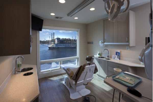 Dental office room with a chair facing a large window overlooking water.
