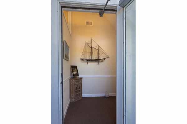 View through doorway into a small room with nautical decor, including a ship sculpture on the wall and a cabinet.