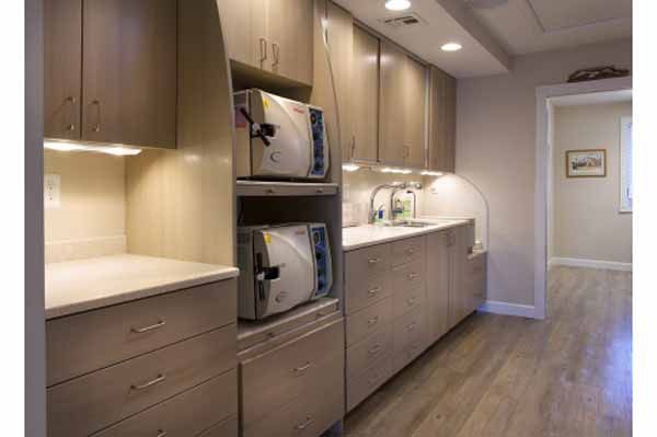 Dental office sterilization room with autoclaves, cabinets, and a sink.