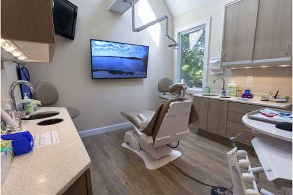 Dental examination room with a patient chair, a TV, and cabinetry.