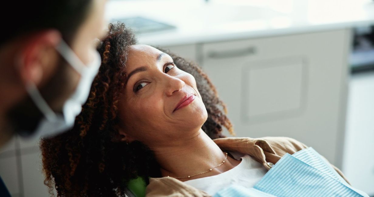 Dental patient reclining in a chair while a clinician leans in nearby