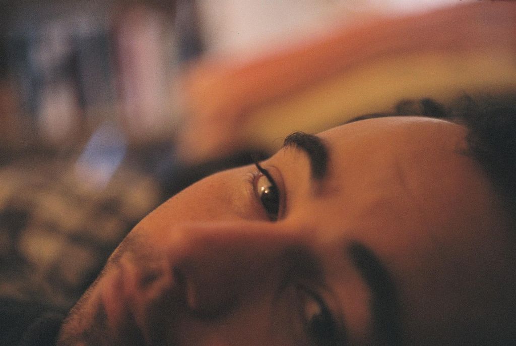 Close-up of a person's face looking up, warm lighting.