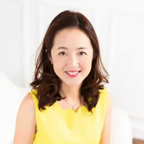 Smiling woman in a sleeveless yellow top against a bright white background