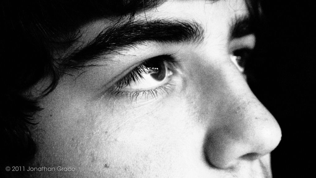 Close-up of a person's face, looking up with a contemplative expression, in black and white.