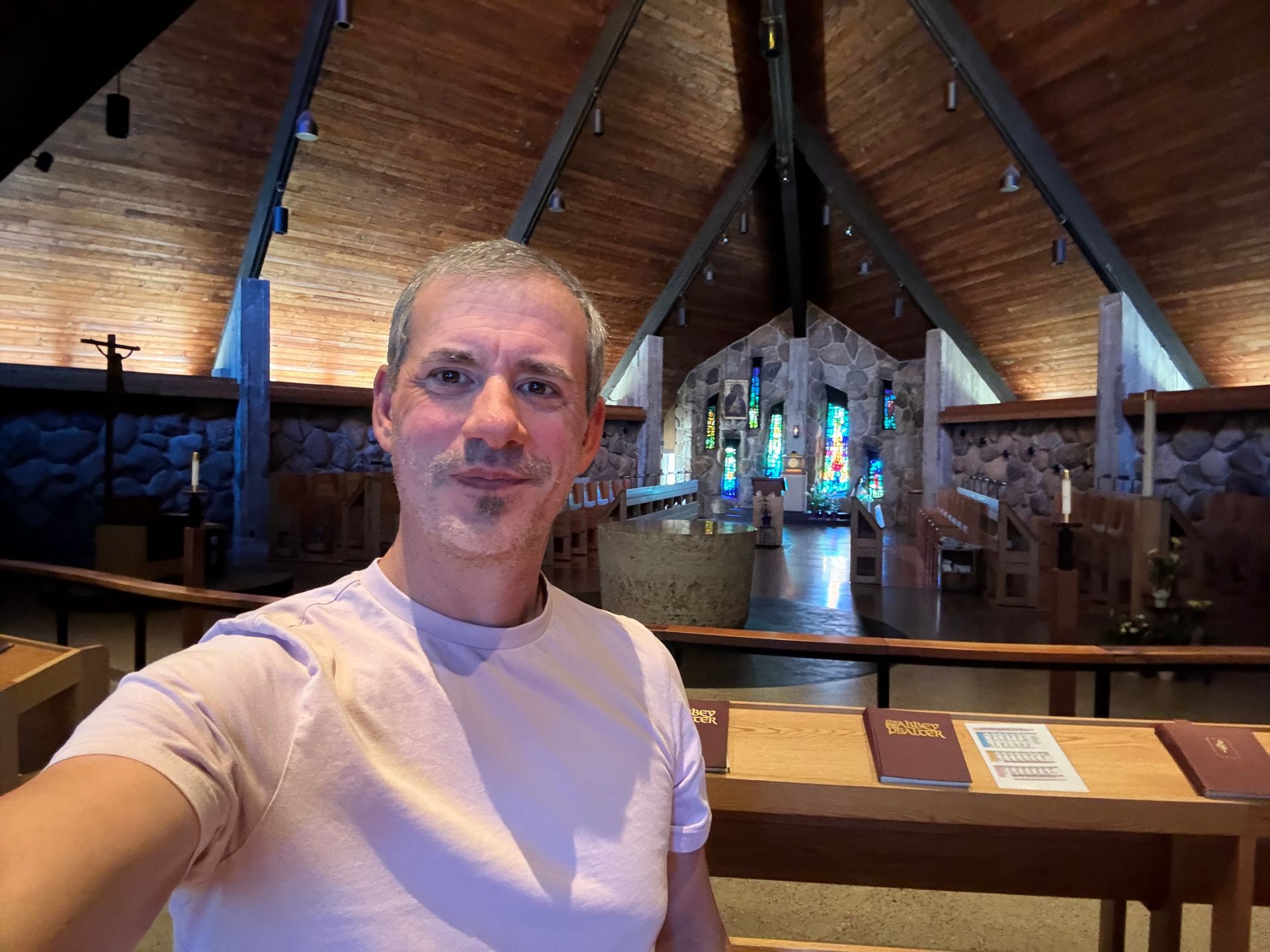 Person taking a selfie inside a wooden church with stained glass and altar in the background