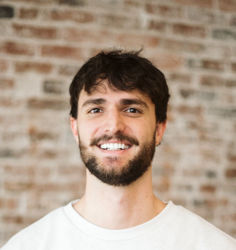 Smiling man in a white shirt against a brick wall background