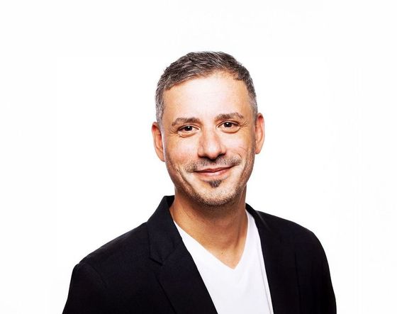 Portrait of a smiling man in a black blazer and white shirt on a white background