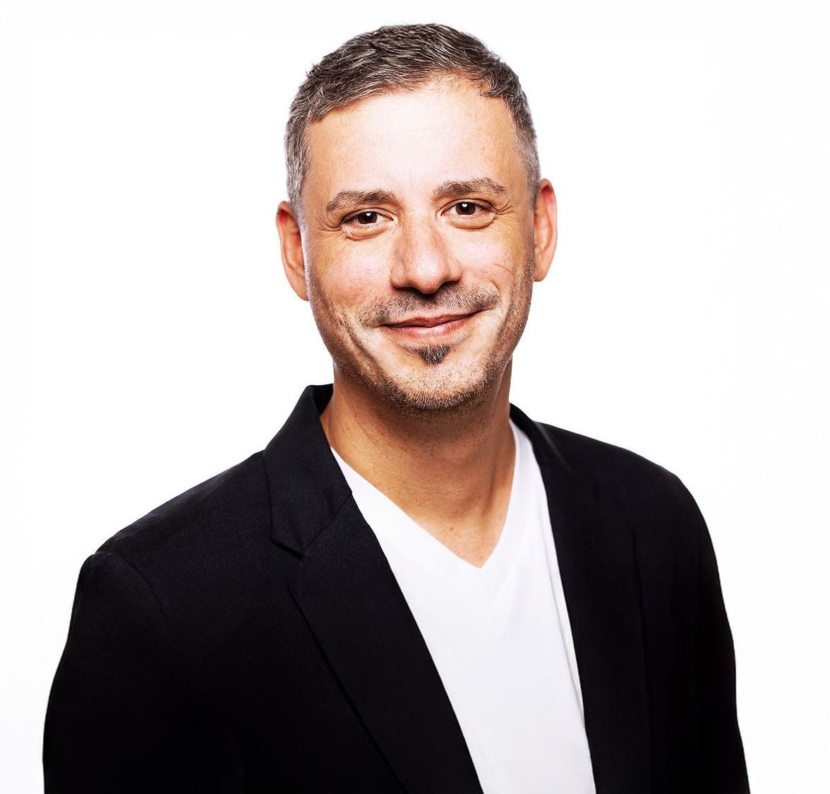 Smiling man in a black blazer over a white shirt on a plain white background
