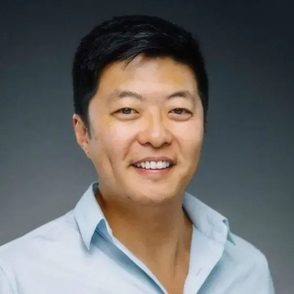 Smiling man in a light blue shirt against a dark gray background